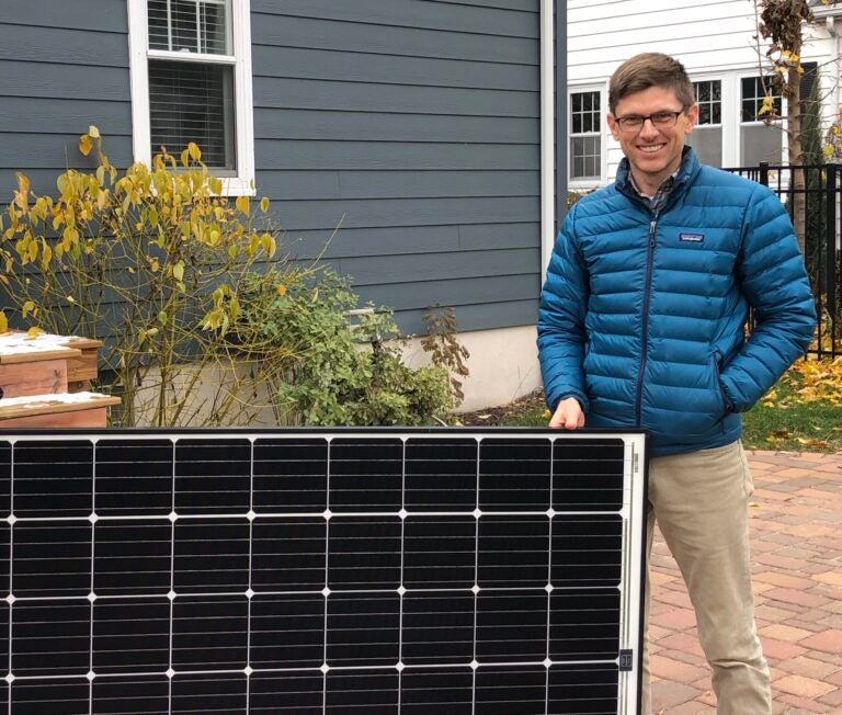 John Farrell stands in front of solar panel after the passing of a landmark community solar law in Minnesota